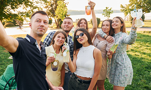 Friends sharing drinks and laughter in the park, embodying the vibrant social experiences on Melt.